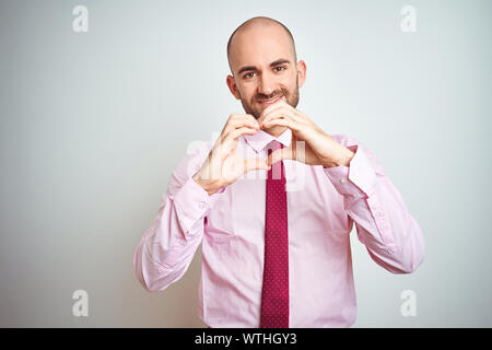 Entreprise jeune homme portant cravate rose sur fond isolé smiling in love montrant le symbole de coeur et la forme des mains. Concept romantique. Banque D'Images