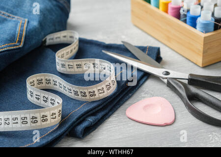 Jeans avec raccourcissement des ciseaux, ruban à mesurer et de la craie. Coupe de jeans ou de réparation. Banque D'Images