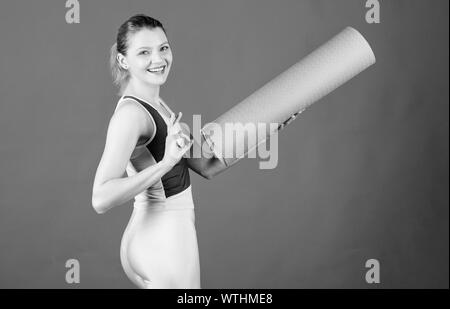 Cours de concept. Le yoga comme passe-temps et le sport. La pratique du yoga tous les jours. Girl smiling slim fit tapis de sol fitness hold de l'athlète. Remise en forme et stretching. L'étirement des muscles. Entrer dans la rainure de yoga. Banque D'Images