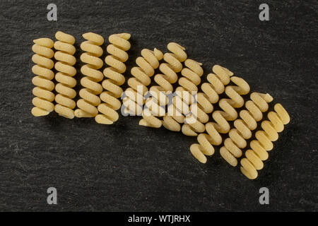 Groupe de onze entiers et frais fusilli bucati pâtes crues sur flatlay pierre gris Banque D'Images