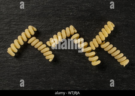 Groupe de six entiers et frais fusilli bucati pâtes crues sur flatlay pierre gris Banque D'Images