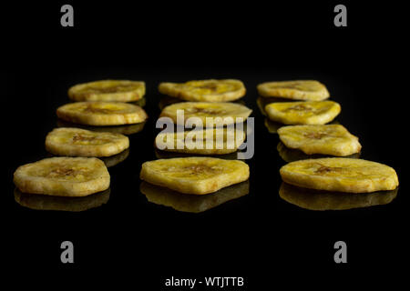 Beaucoup de tranches de banane sec jaune isolé sur verre noir Banque D'Images