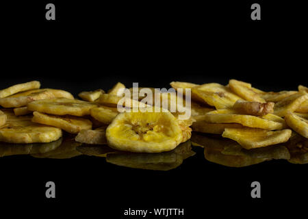 Beaucoup de tranches de banane sec jaune isolé sur verre noir Banque D'Images