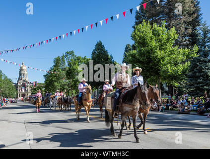 Canada (et buckboard-équitation) cowboys et cowgirls en descendant Capitol Avenue dans l'un des plusieurs parades au cours de la célébration annuelle de Cheyenne Frontier Days dans la ville du même nom. Le Wyoming Capitol est visible derrière les coureurs Banque D'Images