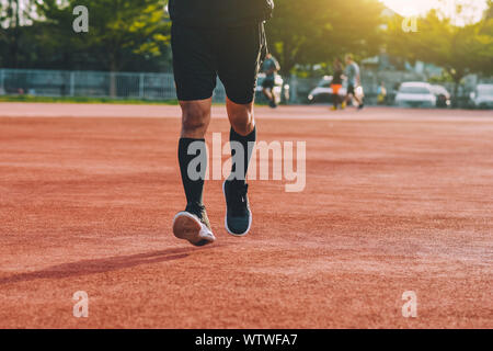Runner homme jogging ou course en soirée à la lumière du soleil Banque D'Images