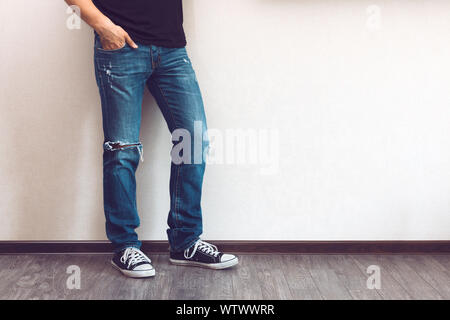 Young Fashion jambes en jeans et baskets sur plancher en bois Banque D'Images