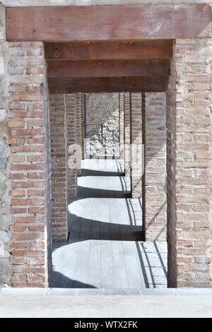 Peniscola, Castellon, Espagne, 08 Septembre 2019 : un couloir avec une structure en briques rouges avec des ombres en forme d'arches. Vertical image Banque D'Images