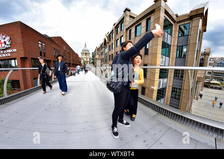 Londres, Angleterre, Royaume-Uni. Les touristes japonais en prenant un sur le Millennium Bridge selfies Banque D'Images