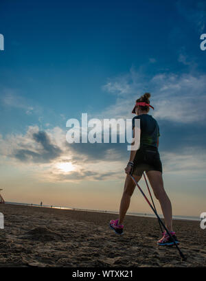 Femme de la marche nordique sur la plage le matin Banque D'Images