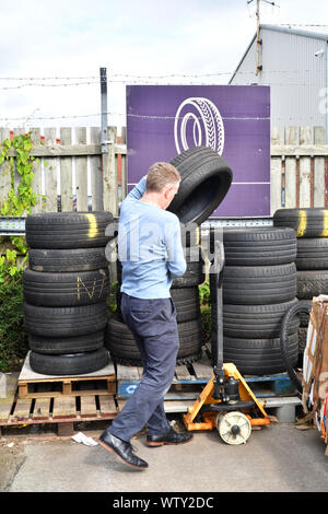 En prenant l'homme pour le recyclage des pneus de véhicule automobile au centre de recyclage du Royaume-Uni Banque D'Images