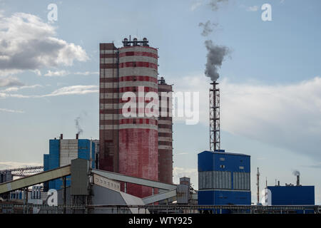 Vue d'un complexe de bâtiments industriels avec des cheminées de fumer dans l'après-midi contre le ciel avec les nuages. Les émissions atmosphériques nocives. Mauvaise l'écologie. Banque D'Images