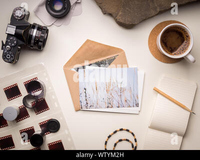 La vie toujours dans des couleurs chaudes avec vintage camera, les rouleaux de film, des cartes postales, notepad et tasse de café Banque D'Images