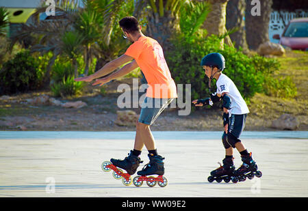 Barcelone, Espagne, le 28 août 2019 : Les enfants apprendre à patiner dans la ligne joyeusement à le parc en été. Les patins à roues alignées l'initiation de l'apprentissage. Banque D'Images