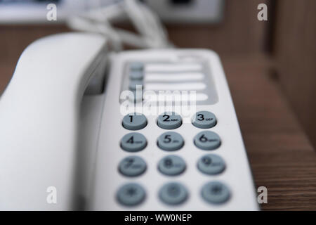 Téléphone vintage blanc gris avec battoms sur une table marron dans l'hôtel. Banque D'Images