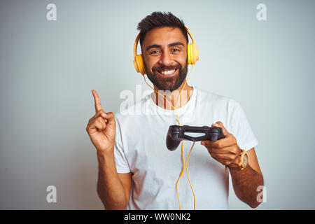 Les indiens arabes gamer man playing video game de l'utilisation des écouteurs sur fond blanc isolé très heureux pointant avec la main et le doigt sur le côté Banque D'Images