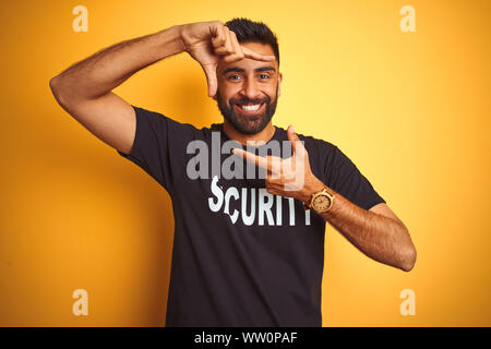 Sauvegarde hispanique indienne arabe homme portant un uniforme de sécurité sur fond jaune isolé du châssis en souriant avec les mains et les doigts avec happy fac Banque D'Images