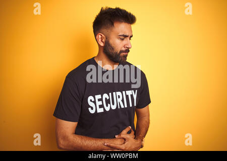 Sauvegarde hispanique indienne arabe homme portant un uniforme de sécurité sur fond jaune isolé avec la main sur l'estomac à cause des nausées, maladie douloureuse feeli Banque D'Images