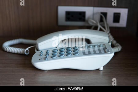 Téléphone vintage blanc gris avec battoms sur une table marron dans l'hôtel. Banque D'Images