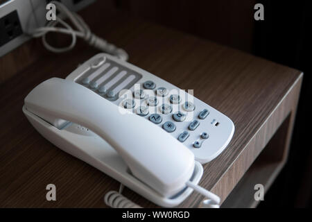 Téléphone vintage blanc gris avec battoms sur une table marron dans l'hôtel. Banque D'Images