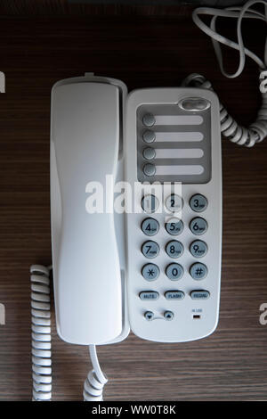Téléphone vintage blanc gris avec battoms sur une table marron dans l'hôtel. Banque D'Images