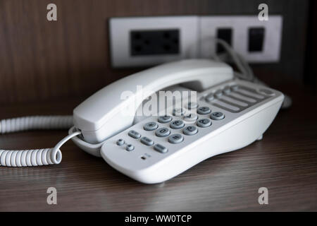 Téléphone vintage blanc gris avec battoms sur une table marron dans l'hôtel. Banque D'Images