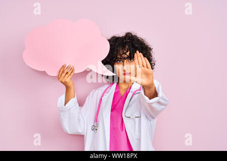 Jeune femme arabe avec des cheveux bouclés holding bulle nuage isolé sur fond rose avec main ouverte faisant stop avec sérieux et confiance e Banque D'Images