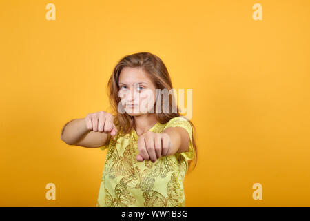 Fille brune en t-shirt jaune isolé sur fond orange montre les émotions Banque D'Images