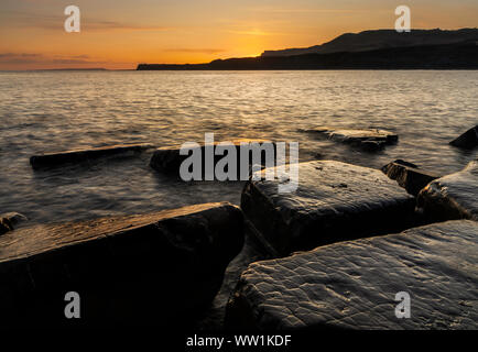 Dorset Kimmeridge Angleterre marée basse expose les rochers de Kimmeridge bay, vu au coucher du soleil Banque D'Images