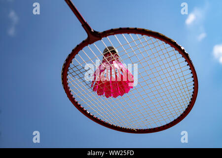 Volant à plumes rose sur racket contre un ciel bleu Banque D'Images