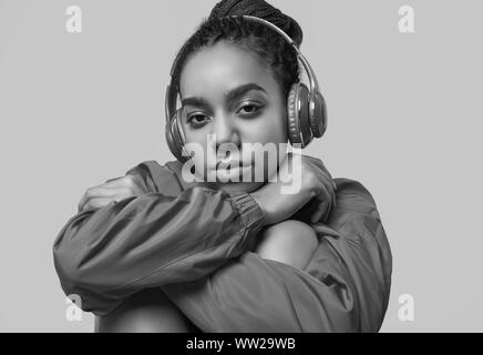 Portrait de l'Afrique belle brunette woman avec des dreadlocks portant un coupe-vent rouge à l'écoute de la musique via un casque sans fil isolé sur vivi Banque D'Images