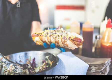 Close up of chef holding fresh hot dog avec saucisse grillée. Banque D'Images