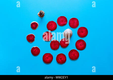 Tranches de betterave rouge affiché dans une spirale sur fond bleu. Voir ci-dessus d'un tourbillon de tranches de betterave. Légumes d'hiver biologique. Châssis de légumes racines Banque D'Images