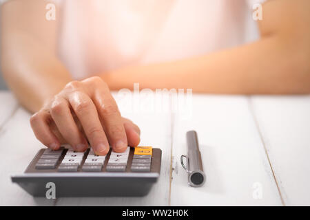 Femme d'affaires à l'aide d'une calculatrice sur le bureau, choisissez Focus point. Dans la lumière. Banque D'Images