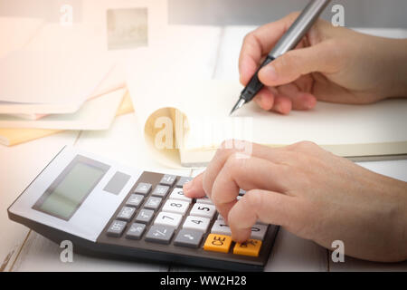 Part l'écriture et du calcul sur calculatrice de bureau Le bureau bois à propos de l'analyse des données financières, choisissez point focus. Banque D'Images