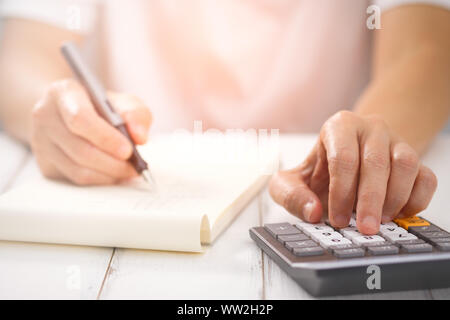 Part l'écriture et du calcul sur calculatrice de bureau Le bureau bois à propos de l'analyse des données financières, choisissez point focus. En plus de la lumière. Banque D'Images