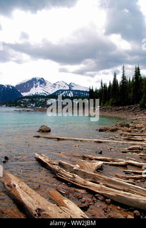 Bleu glacier Garibaldi lake aux cimes enneigées des montagnes de l'horizon et un ciel nuageux blanc brillant, sur un sentier de randonnée dans le parc provincial Garibaldi Banque D'Images