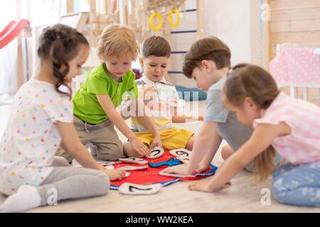 Les enfants s'asseoir sur le plancher rondes en maternelle. Les enfants d'âge préscolaire d'apprendre à lire l'heure de réveil et de mettre les mains dans la position correcte. Du vrai peop Banque D'Images