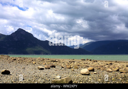 La vue paisible de Howe Sound baie turquoise avec la plage de rochers et de montagnes côtières sur un jour nuageux et venteux dans le parc provincial Porteau Cove Banque D'Images