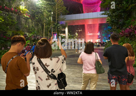 Singapour - CIRCA AVRIL 2019 : femme prendre photo de 40 mètres, la pluie, la HSBC Vortex le plus grand du monde cascade intérieure à l'aéroport de Changi Jewel at nigh Banque D'Images