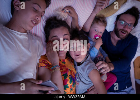 Family lying on bed at home Banque D'Images