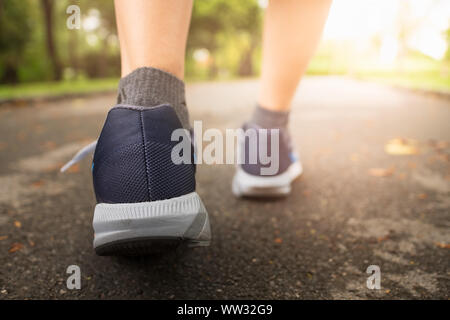 Jogging femme dans Central Park en portant des chaussures de sport de l'exercice dans la soirée coucher du soleil. Banque D'Images