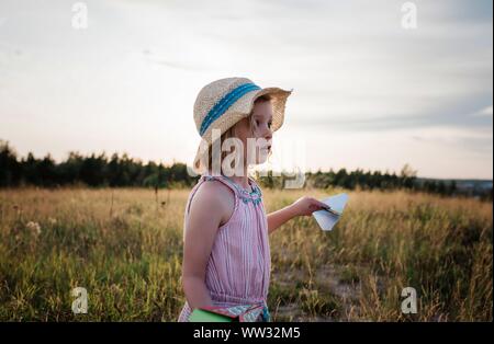 Portrait d'une jeune fille jouant avec paper planes dans un pré Banque D'Images