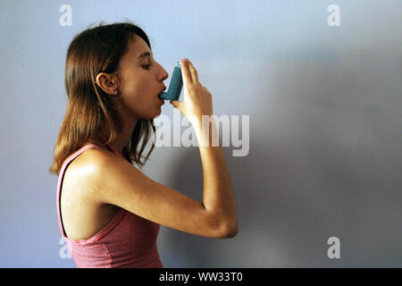 Santé et médecine - Jeune fille à l'aide Asthme inhalateur bleu pour prévenir une attaque d'asthme. Produits pharmaceutiques pour prévenir et traiter l'asthme. Banque D'Images