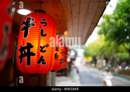 Taipei, Taïwan : lanterne traditionnelle japonaise l'écriture japonaise avec pendaison le Restaurant du trottoir dans petite rue avec arrière-plan flou Banque D'Images