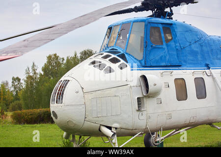 Petit hélicoptère blanc avec une bande bleue sur l'herbe verte. Banque D'Images