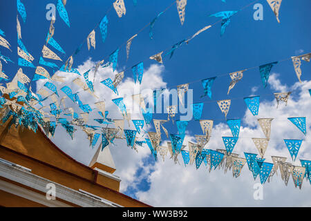 Décoration de drapeaux bleu et blanc accroché sur les rues de Puebla, Mexique. mois patriotique, décoration typique maison jaune et bleu ciel. Ils ont des traditions mexicaines : gastronomique, de l'architecture coloniale et la céramique. Carreaux talavera peintes ornent des édifices anciens. La cathédrale de Puebla, de style Renaissance, a une tour clocher donnant sur le Zocalo, la place centrale ou Place Zocalo. J'entre dans l'histoire. L'architecture est un UNESCO World Heritage Site. Attractions : Cathédrale, Temple de Notre-Dame de Concord, ancien collège Carolino, Bibliothèque Palafoxiana, Temple de Santo Domingo. (© P Banque D'Images