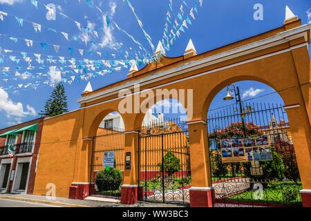 Décoration de drapeaux bleu et blanc accroché sur les rues de Puebla, Mexique. mois patriotique, décoration typique maison jaune et bleu ciel. Ils ont des traditions mexicaines : gastronomique, de l'architecture coloniale et la céramique. Carreaux talavera peintes ornent des édifices anciens. La cathédrale de Puebla, de style Renaissance, a une tour clocher donnant sur le Zocalo, la place centrale ou Place Zocalo. J'entre dans l'histoire. L'architecture est un UNESCO World Heritage Site. Attractions : Cathédrale, Temple de Notre-Dame de Concord, ancien collège Carolino, Bibliothèque Palafoxiana, Temple de Santo Domingo. (© P Banque D'Images