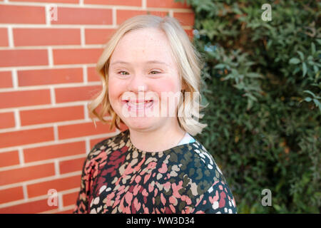 Smiling teen girl with Down Syndrome par mur de brique à San Diego Banque D'Images