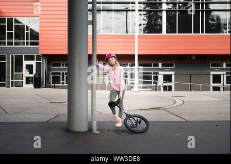 Jeune fille appuyée sur colonne avec l'environnement urbain en monocycle Banque D'Images