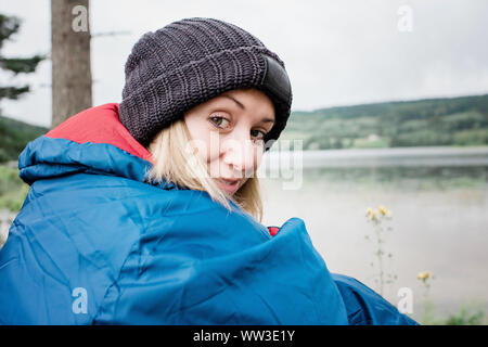 Portrait d'une femme avec un chapeau dans un sac de couchage camping en vacances Banque D'Images